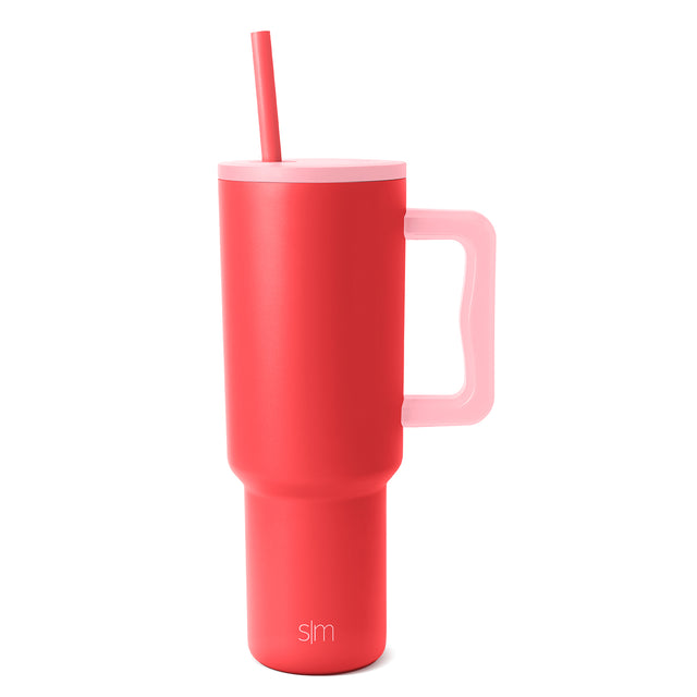 Coral red insulated tumbler with soft pink lid, matching straw, and pink-accented handle rim Coral red insulated tumbler with soft pink lid, matching straw, and pink-accented handle rim