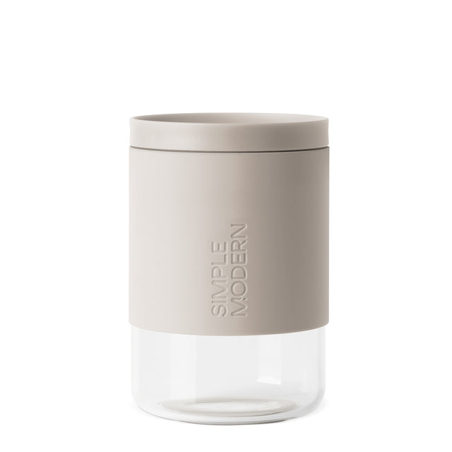 Warm beige and taupe cylindrical product with clear glass lower section against neutral background Warm beige and taupe cylindrical product with clear glass lower section against neutral background