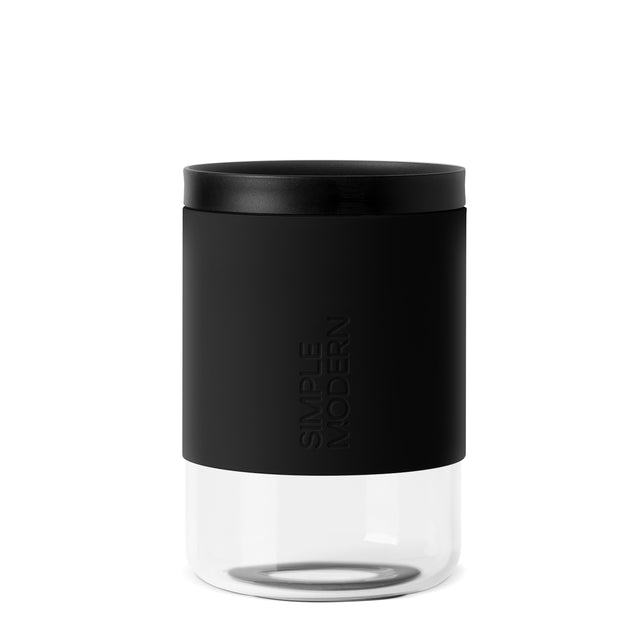 Matte black cylindrical container with white lower section and black lid, shown against white background. Matte black cylindrical container with white lower section and black lid, shown against white background.