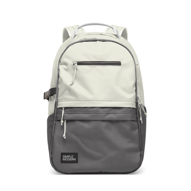Cream and charcoal gray two-tone backpack with gray accent straps and piping trim along the edges where the colors meet. Cream and charcoal gray two-tone backpack with gray accent straps and piping trim along the edges where the colors meet.