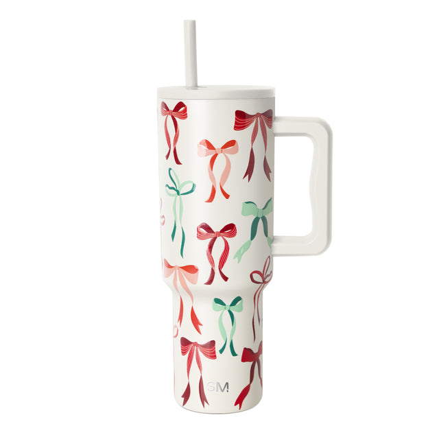 Cream and off-white tumbler with festive repeating red, coral, pink, and sage green bow pattern Cream and off-white tumbler with festive repeating red, coral, pink, and sage green bow pattern