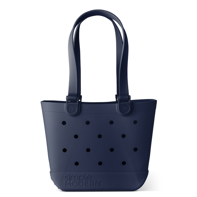 Navy blue tote bag with black circular perforations, shown against a white background. Simple modern design featuring structured shape and handles for carrying. Navy blue tote bag with black circular perforations, shown against a white background. Simple modern design featuring structured shape and handles for carrying.