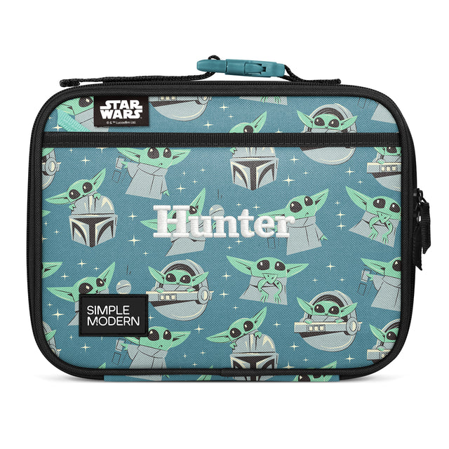 Dusty blue-teal insulated lunch bag with Grogu and Mandalorian helmet pattern, black mesh pocket with teal zipper, webbing handle, labeled Dusty blue-teal insulated lunch bag with Grogu and Mandalorian helmet pattern, black mesh pocket with teal zipper, webbing handle, labeled