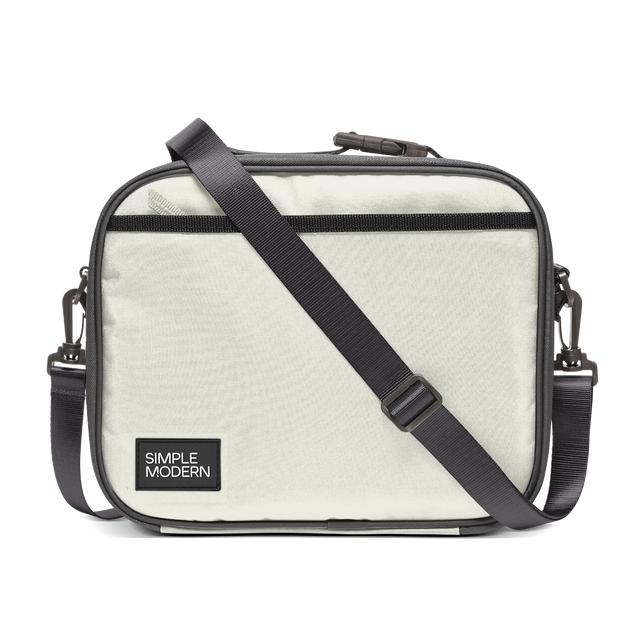 Light cream canvas tote bag with charcoal gray trim, black webbing straps, and dark hardware. Front view of structured handbag with contrasting accent details. Light cream canvas tote bag with charcoal gray trim, black webbing straps, and dark hardware. Front view of structured handbag with contrasting accent details.