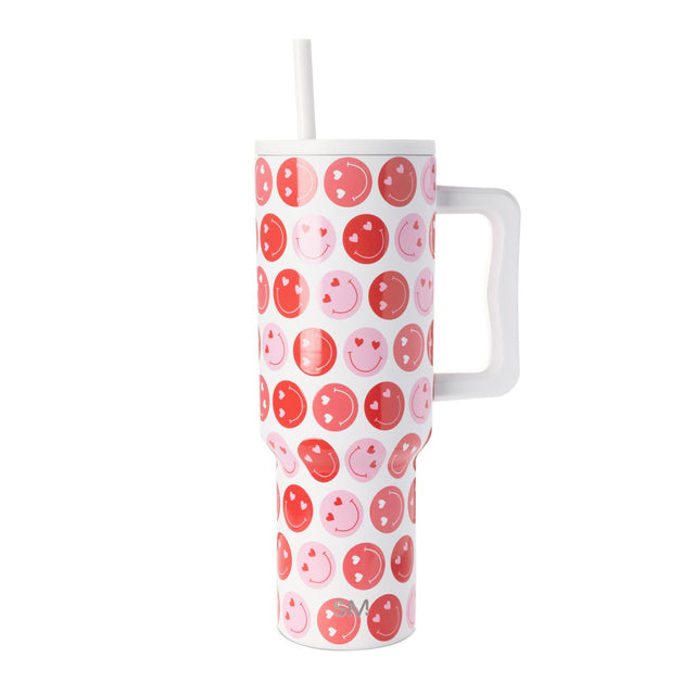 White tumbler with repeating smiley face designs in coral red, hot pink, and light pink. White cap, handle, and straw included. White tumbler with repeating smiley face designs in coral red, hot pink, and light pink. White cap, handle, and straw included.