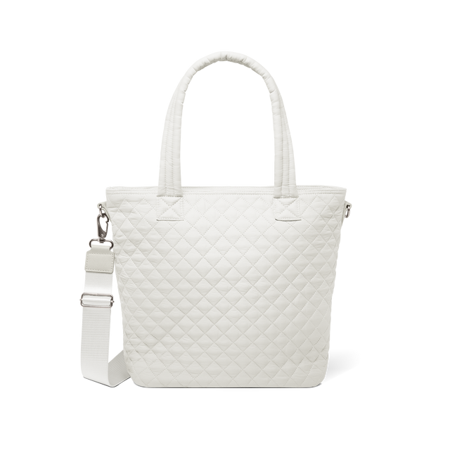 Cream-colored quilted tote bag with dual white handles against a white background Cream-colored quilted tote bag with dual white handles against a white background