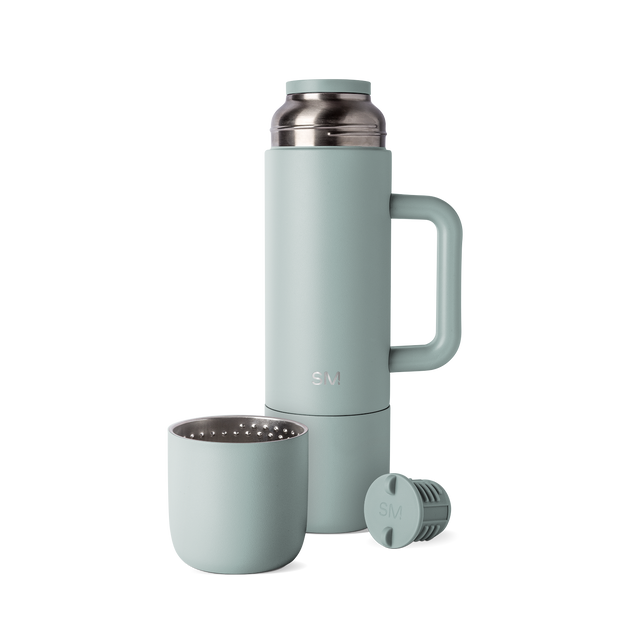 Sage green insulated thermos with matching cap and cup, displayed with handle and accessories against white background Sage green insulated thermos with matching cap and cup, displayed with handle and accessories against white background