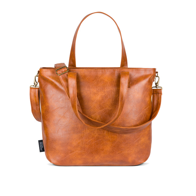 Cognac brown leather handbag with golden undertones against white background Cognac brown leather handbag with golden undertones against white background
