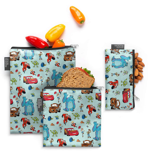 Three reusable food storage bags displayed against a pale blue-green background, featuring bright red, yellow, and orange accents on each bag. Three reusable food storage bags displayed against a pale blue-green background, featuring bright red, yellow, and orange accents on each bag.