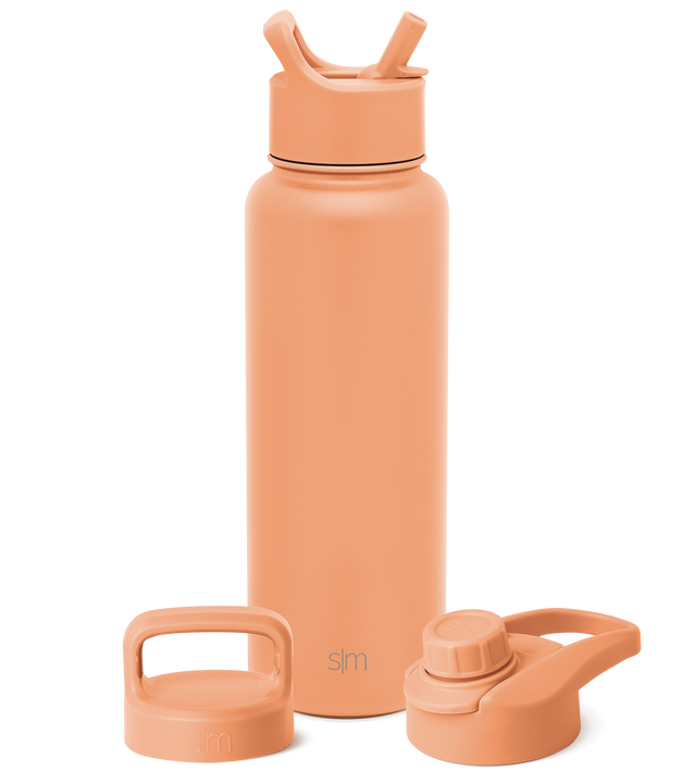 Peachy-coral colored bottle with matching accessories on white background Peachy-coral colored bottle with matching accessories on white background