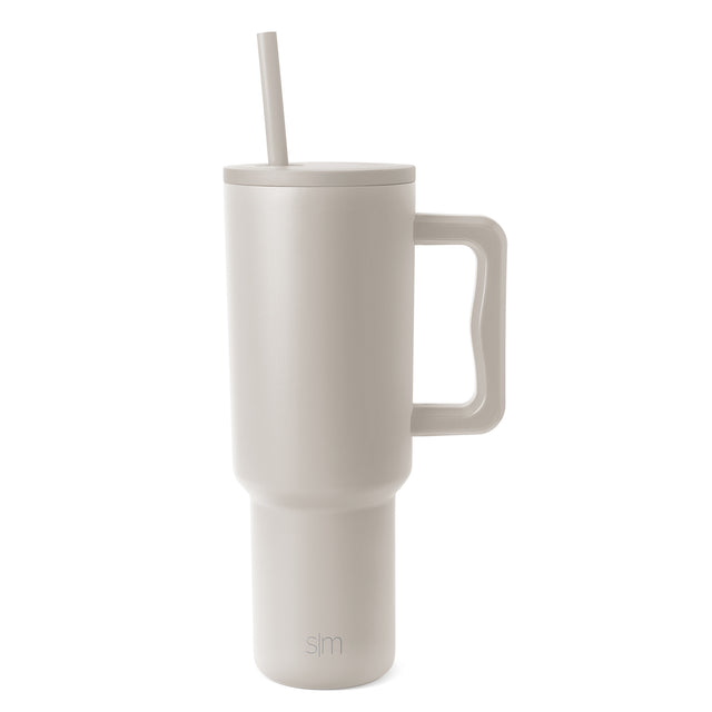 Trek Tumbler in cream color with matching lid and straw, featuring an integrated handle and Simple Modern logo, isolated on white background.