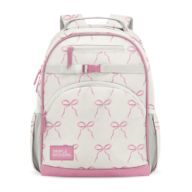 Cream and pink children's backpack with bow pattern, zippered pockets, mesh side compartments, padded straps, and Simple Modern branding label on front pocket.