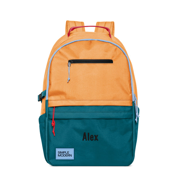Colorblock backpack with peachy-orange top, periwinkle trim, and teal bottom, featuring magenta-pink padded straps, black zippered pocket, and 