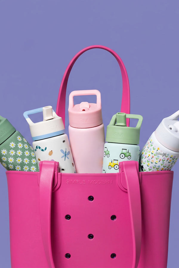 Hot pink Simple Modern tote bag filled with five colorful water bottles featuring floral and nature designs, set against a soft purple background.
