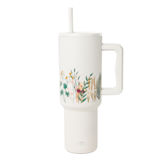 Cream-colored tumbler with botanical leaf design wrapping around the upper portion, modern minimalist style.