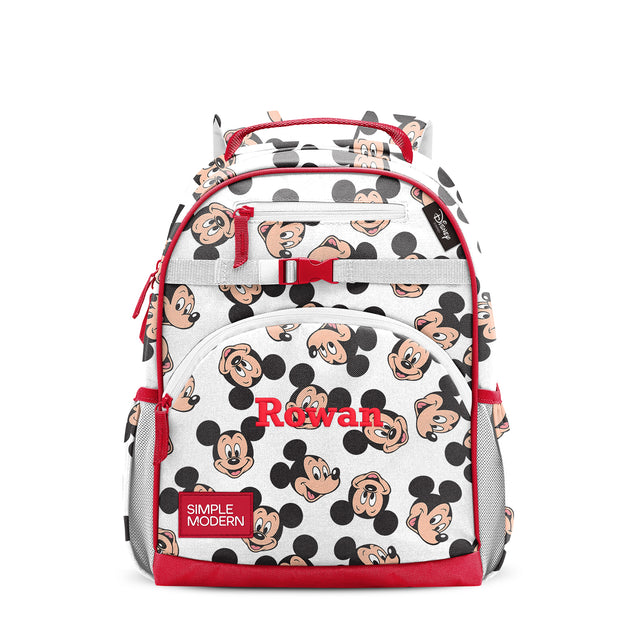 White children's backpack with red trim, black circles and peach character faces pattern, multiple zippered compartments, padded red straps, gray mesh side pockets, personalized with 