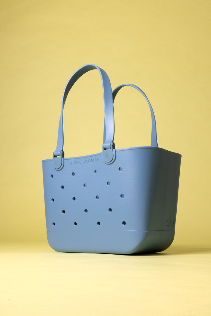 Periwinkle-blue tote bag with grid pattern of small circular ventilation holes on front, displayed against pale yellow background.