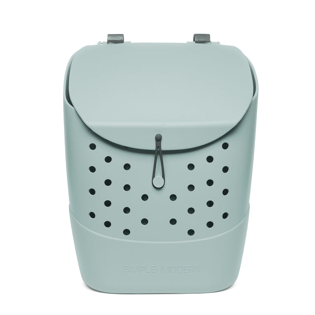 Sage green structured backpack with black perforated ventilation pattern, gray metal handles, black drawstring cord, and curved flap closure. Simple Modern branding visible on front. Studio product photo on white background.