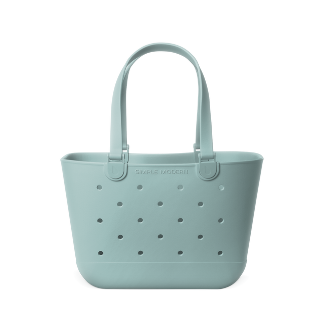 Soft sage green tote bag displayed against a neutral background. The bag features sturdy handles and a spacious rectangular silhouette, shown in a muted celadon blue-green tone throughout.