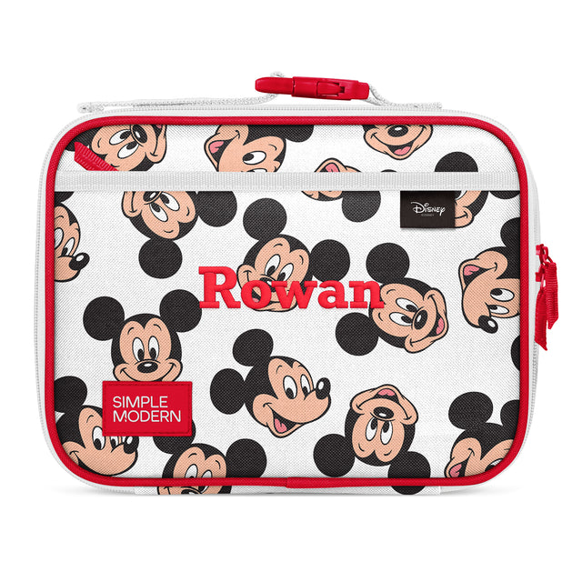 White insulated lunch box with red accents, featuring repeating Mickey Mouse character faces, red handle and zippers, mesh panel at bottom. Simple Modern brand and Rowan label visible. Disney merchandise product shot.