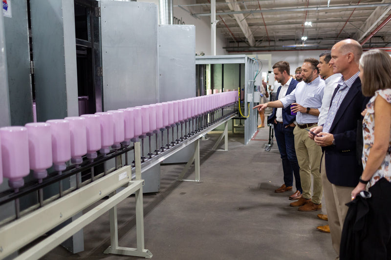Rows of soft pink cylindrical drinkware displayed on an industrial production line