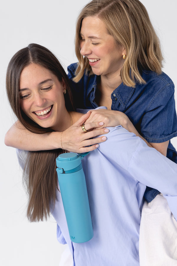 Soft turquoise blue drinkware displayed next to a person wearing a light periwinkle long-sleeved shirt