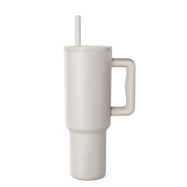 Beige signature tumbler with handle and straw on neutral background