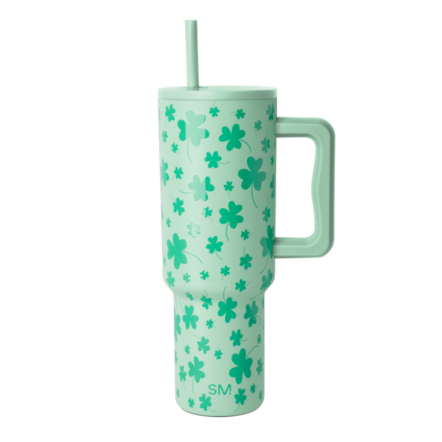 Tall cylindrical mint green tumbler with handle and reusable straw against white background