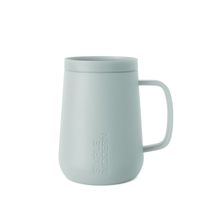 Soft sage green ceramic mug with handle on light gray background