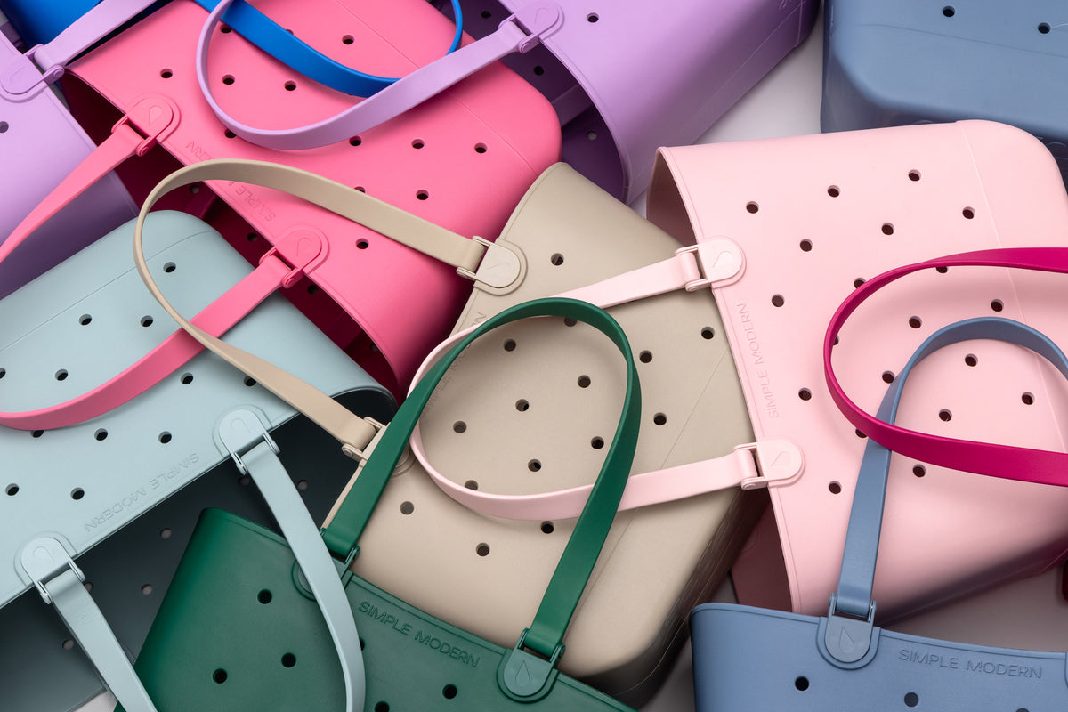 Overhead view of Getaway Bag totes stacked in many colours including lavender, hot pink, sage, sand and slate blue.