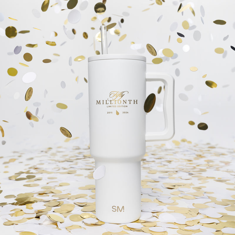 The white Fifty Millionth limited-edition tumbler, marked 2015 to 2024 in gold, standing amid gold and white confetti