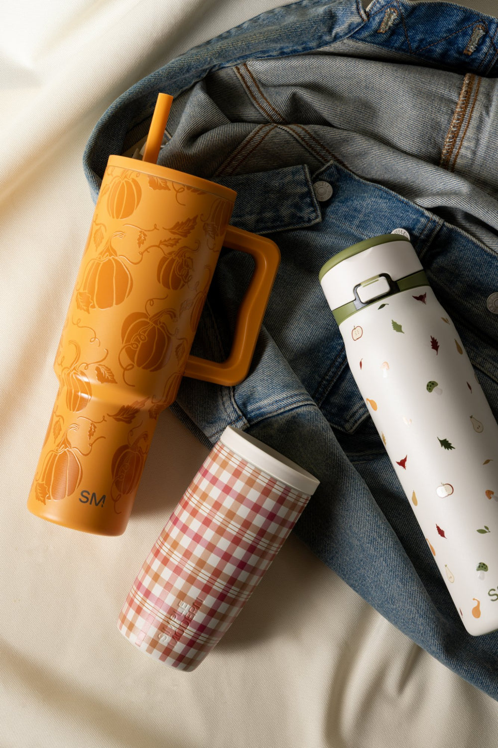 Simple Modern fall-pattern tumblers and bottle laid on a denim jacket